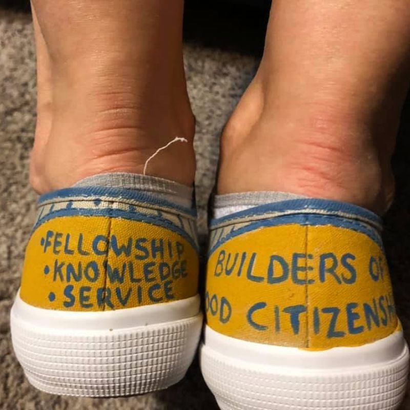Yellow sneakers with words Fellowship, Knowledge, Service, Builders of good citizenship