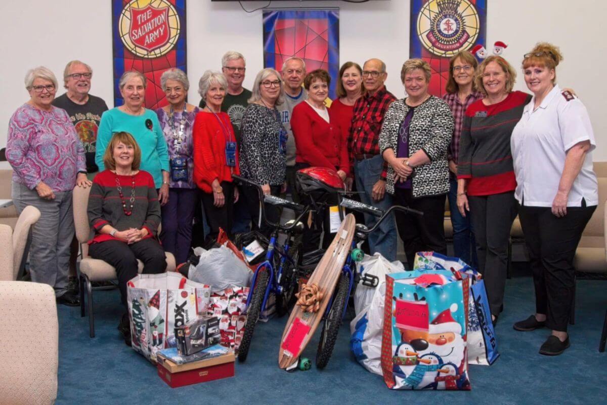 Salvation Army volunteer and Civitans standing with bags of toys and Christmas presents