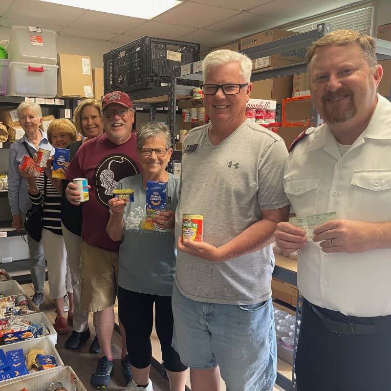 Men and women holding canned food inside commercial kitchen